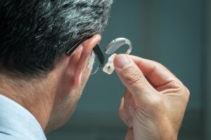 Man inserting hearing aid into his ear