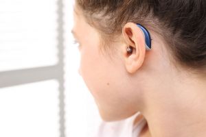 View of young girl's ear with small blue hearing aid