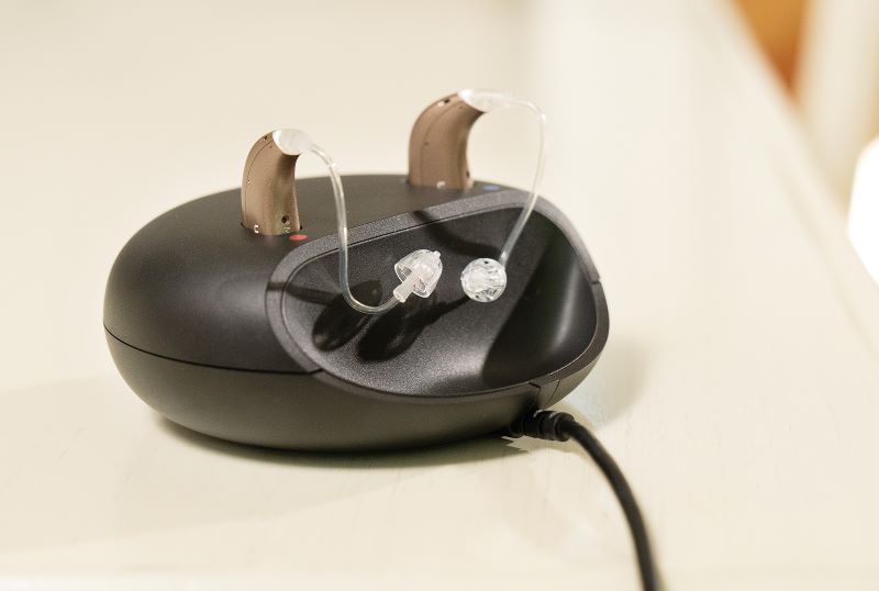 Closeup view of Oticon Real hearing aids in their recharging dock.