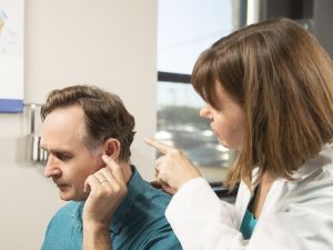 An audiologist examines a man's ear. 