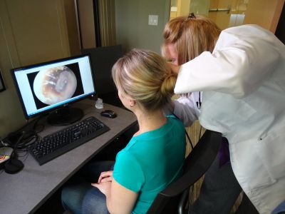 A practitioner examines the patient's ear