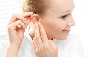 A woman inserts her hearing aid. 