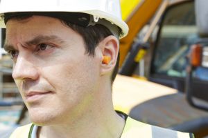 A construction worker wears earplugs.