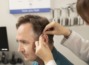 An audiologist adjusts a man's hearing aid. 