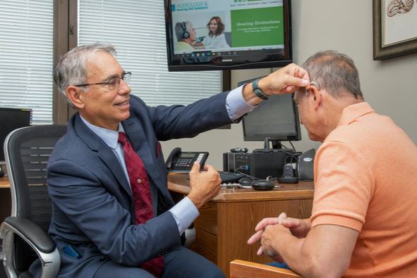 Dr. Pat Biondi fitting hearing aids on a patient