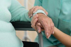 Woman's hand supporting an older woman on walker