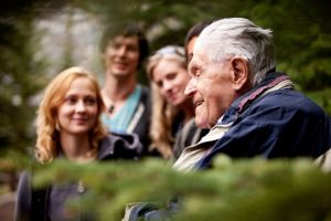 Elderly man talking to a group of young people 