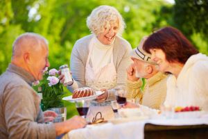 Two mature couples laughing at birthday celebration outdoors