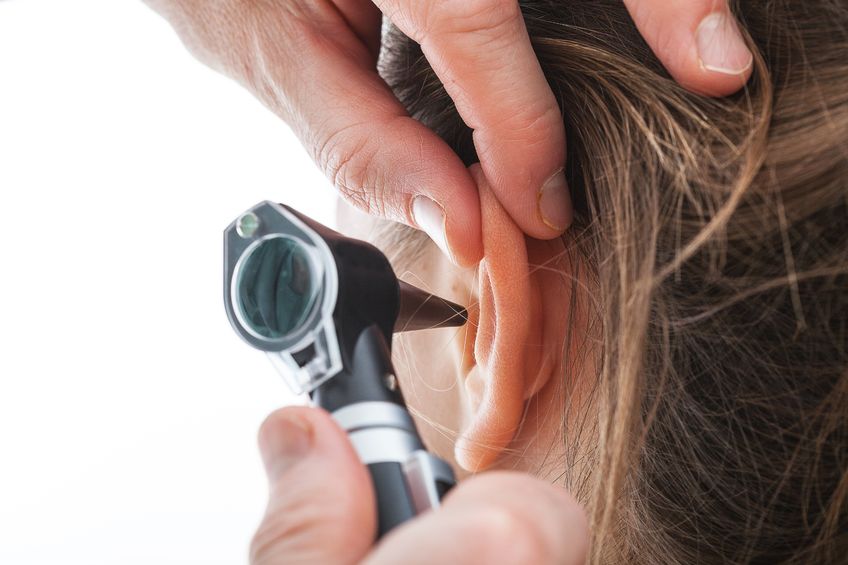 Audiologist looking in ear with otoscope