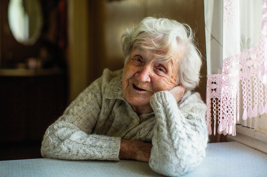 An older woman smiles at the camera. 