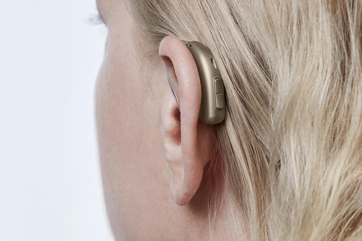 A woman wears a hearing aid with a telecoil.