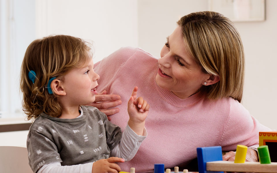 A boy with a cochlear implant speaks to his teacher. 