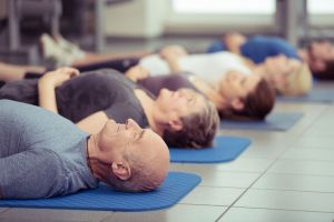 adults lying on floor of gym relaxing after fitness class