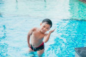 A boy jostles his ear to get water out. 