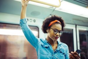A woman listens to music on the subway, using earbuds.