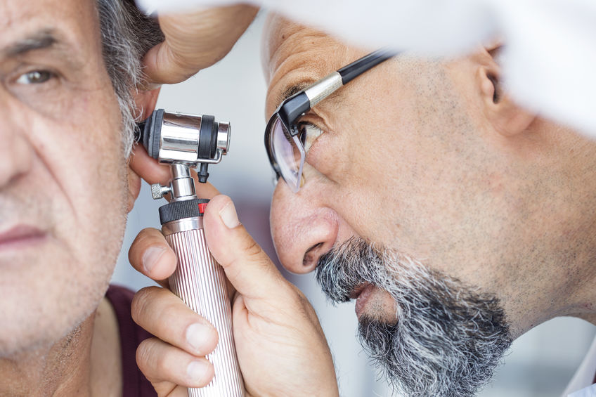 audiologist using otoscope to look into man's ear