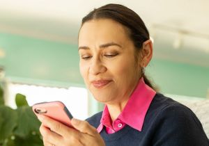 A woman talks on her smartphone while wearing a hearing aid.