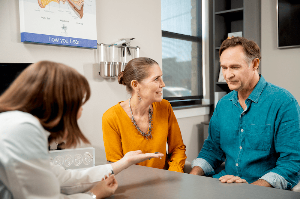 A couple discusses a hearing aid warranty with a hearing care provider. 