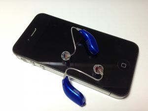 A pair of hearing aids sitting on an iPhone