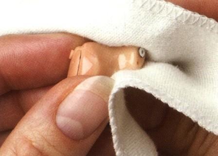 close-up on hearing aid being wiped with soft cloth