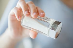 woman's hand holding salt shaker