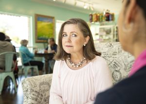 A woman with a hearing aid talks to a friend.