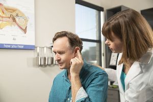 A man points to his ear at the audiologist's office.
