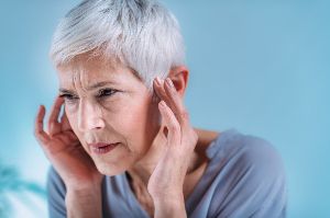 A woman holding her ears in pain.